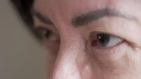 BBC A close up shot of a woman's face, showing just her eyes, eyebrows and top of her nose. She has dark, arched eyebrows and brown eyes.