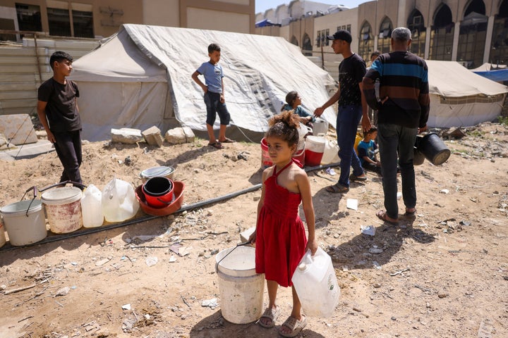 A girl holds plastic containers as displaced Palestinians collect water at a camp in Gaza City, on May 20, 2025.