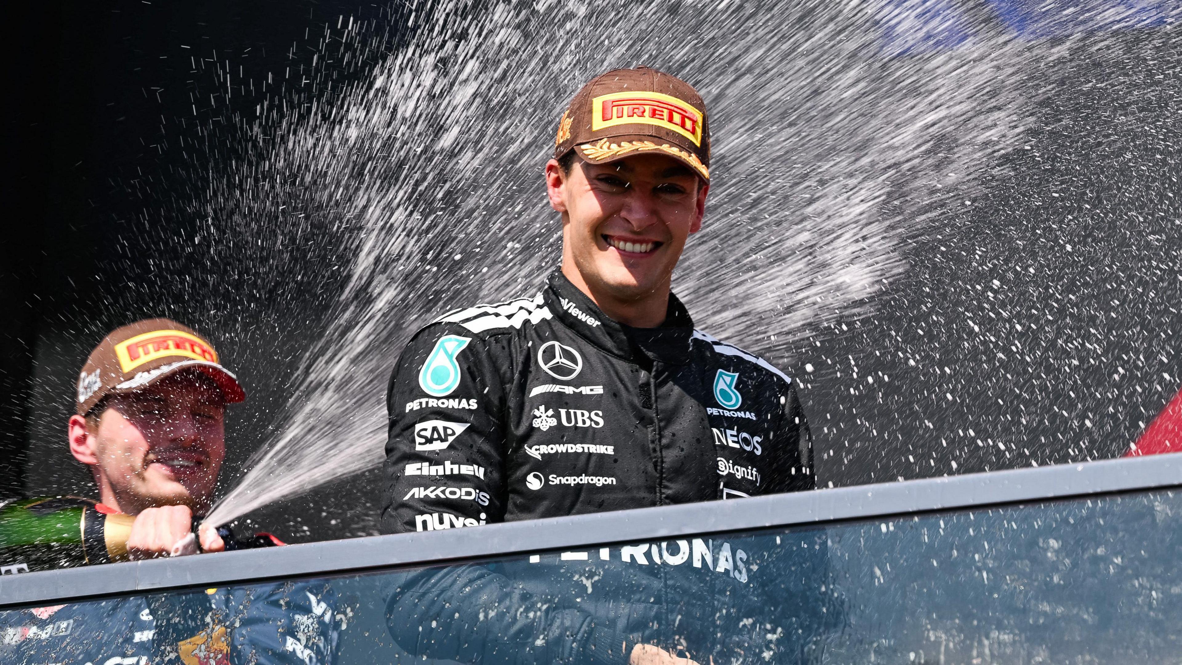 Max Verstappen sprays champagne over race winner George Russell on the podium after the Canadian Grand Prix
