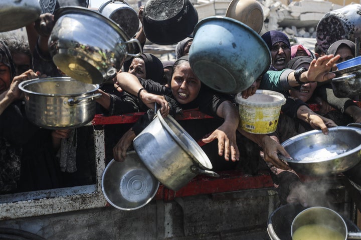Palestinians, struggling with hunger, wait to receive a hot meal distributed by a charity organization in Gaza City on Wednesday as people are unable to reach food.