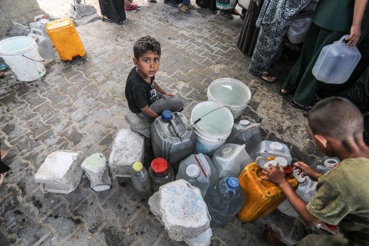 Displaced Palestinians fill containers with water from tankers brought into the area in Khan Younis, Gaza, on July 13, 2025.