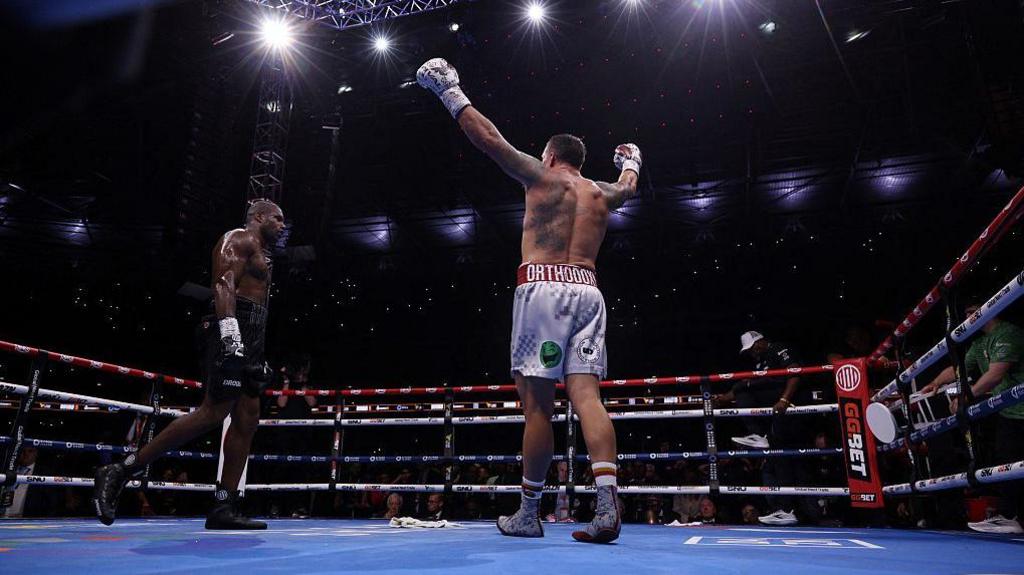 Oleksandr Usyk holds up his arms as Daniel Dubois walks past in the ring at Wembley Stadium