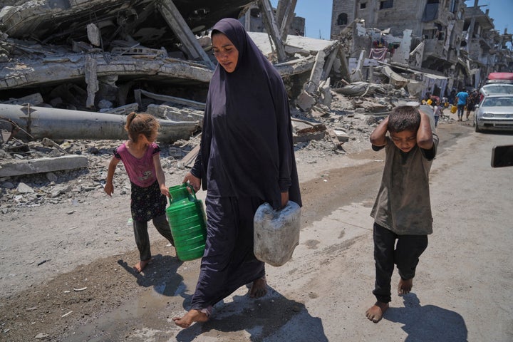 Abeer Sobh and her children carry water in plastic jerrycans after collecting it from a water truck in Gaza City, Thursday, July 24, 2025. (AP Photo/Jehad Alshrafi)