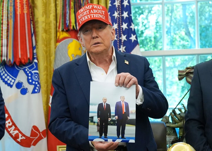 President Donald Trump holds a photo of himself with Russian President Vladimir Putin during an announcement in the Oval Office of the White House, Friday, Aug. 22, 2025, in Washington. (AP Photo/Jacquelyn Martin)