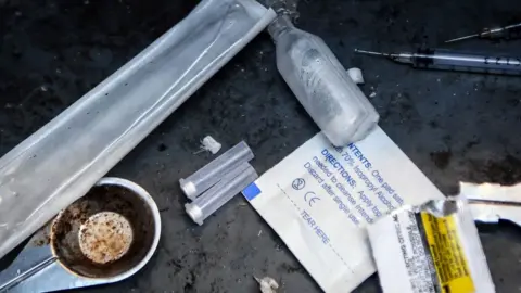 Getty Images Discarded drug paraphernalia, including syringes and small plastic tubes, in a lane in Glasgow.