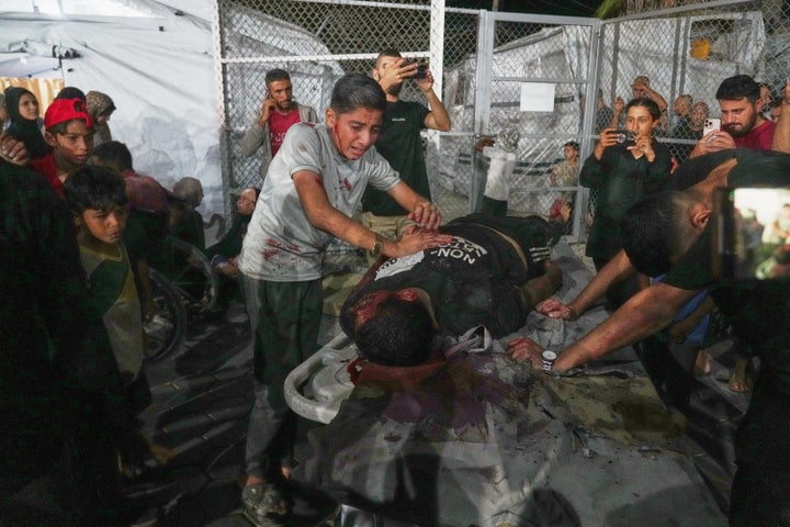 An injured Palestinian boy mourns over the body of a man killed in an Israeli strike on a carpentry shop and a café, as the victim is brought to Al-Aqsa Hospital in central Gaza's Deir al-Balah, on Sept. 30, 2025. 