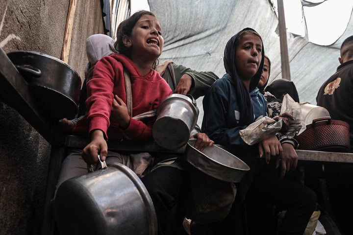 Palestinians children crowd around to receive hot meals from charity organizations in the Nuseirat refugee camp, as people continue to starve due to Israel's ongoing blockade in Gaza City on Oct. 7, 2025.