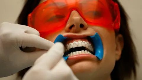 Getty A stock image of a woman in a dentist chair wearing mouth guards and protective glasses.