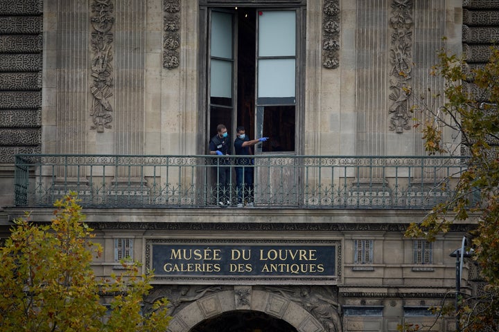 French crime scene officers gesture as they examine the cut window and balcony of a gallery at the Louvre Museum on Oct. 19 in Paris, France.