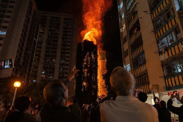 People look at flames engulfing a building after a fire broke out at Wang Fuk Court, a residential estate in the Tai Po district of Hong Kong's New Territories, Wednesday, Nov. 26 2025. (AP Photo/Chan Long Hei)