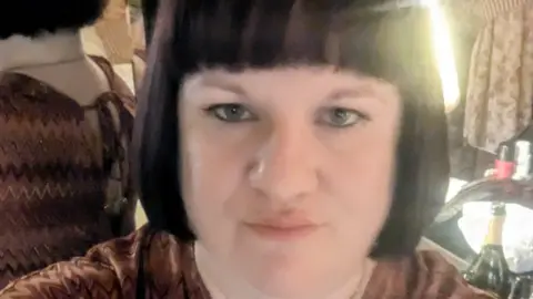 Hayley Barlow-Ford A close-up selfie of a woman with a short black bob and black fringe. 