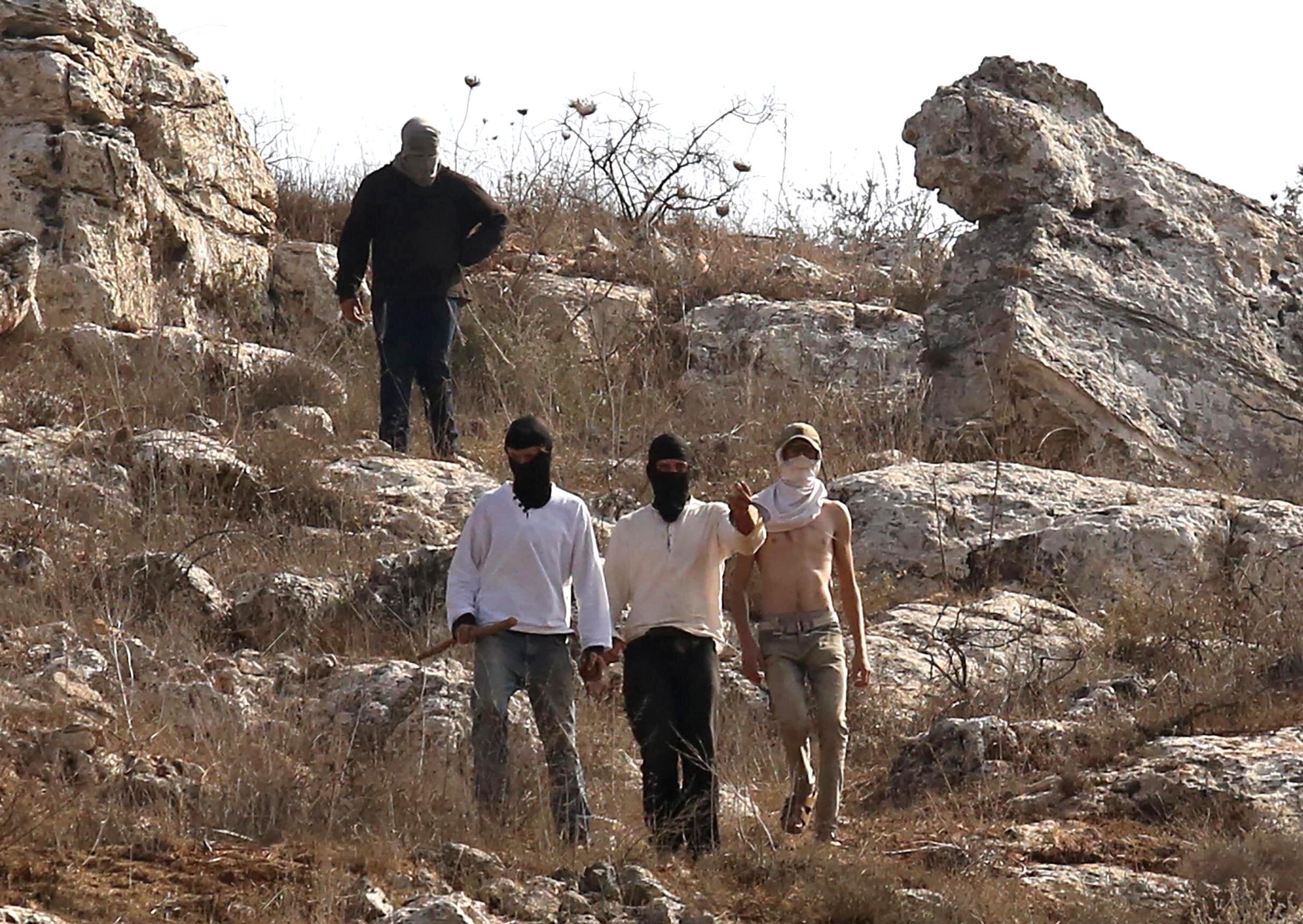 Illegal settlers, covering their faces with masks, attack Palestinian farmers, journalists and foreign activists with sticks and stones in Beita town of Nablus, West Bank on November 08, 2025. (Photo by Nedal Eshtayah/Anadolu via Getty Images)