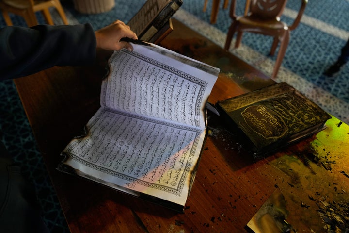 A boy inspects burnt copies of Quran inside a mosque that was torched and defaced by Israeli settlers overnight, in the West Bank town of Deir Istiya Thursday, Nov. 13, 2025. (AP Photo/Nasser Nasser)