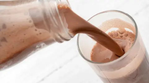 Getty Images Pouring chocolate milk from a plastic bottle into a glass