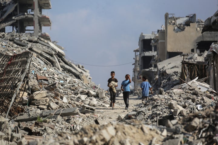 Palestinian boys make their way through the rubble of destroyed buildings in the Al-Shatee refugee camp, east of Gaza City, on November 8, 2025.(Photo by Bashar Taleb / AFP via Getty Images)