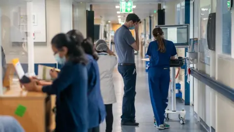 PA Media Health workers stand in a corridor in an NHS hospital.