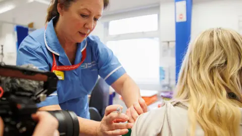 PA Media A healthcare worker administers a flu jab to another person in a healthcare environment at Ulster hospital in Belfast on 4 December.