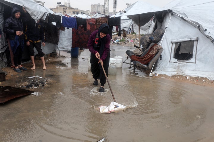 A Palestinian woman clears rainwater in front of her tent after heavy rains in Gaza City, on Dec. 12, 2025.