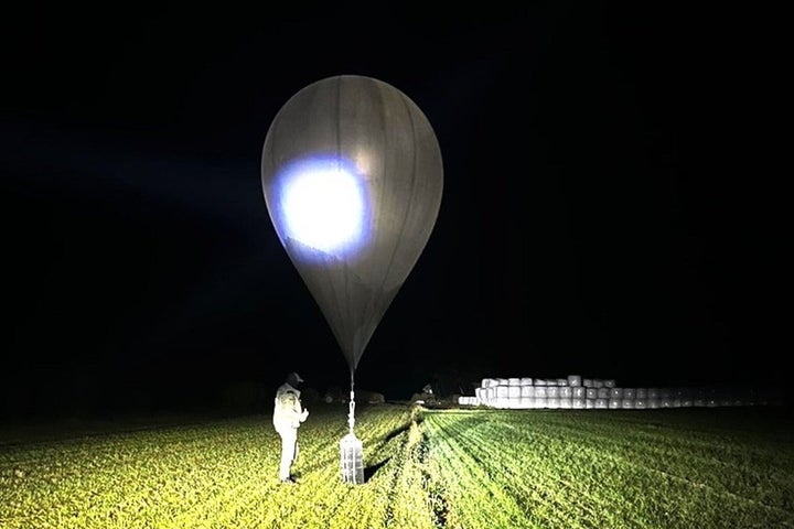 In this undated photo released by the State Border Guard Service, an officer inspects a balloon used to carry cigarettes into Lithuania, because Belarusian smugglers often use them to ferry the contraband into the European Union.