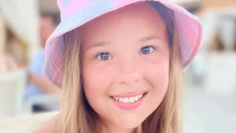 Diabetes UK Imogen, who is 12, wears a pink sun hat and is smiling at the camera