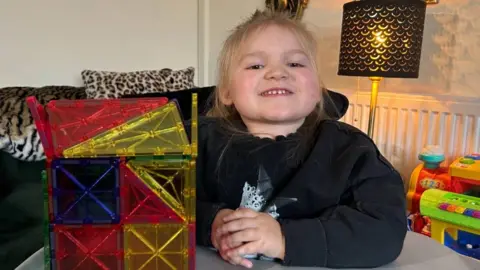 BBC Dani-Rae Brown sat at a table with her elbow on the table. To her right is a multi-coloured plastic cube. 