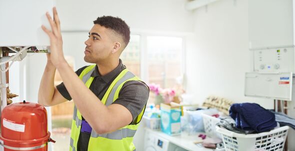 young heating engineer looking at boiler young heating engineer looking at boiler