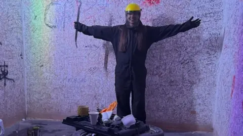 Picture of a woman in a rage room wearing protective clothing