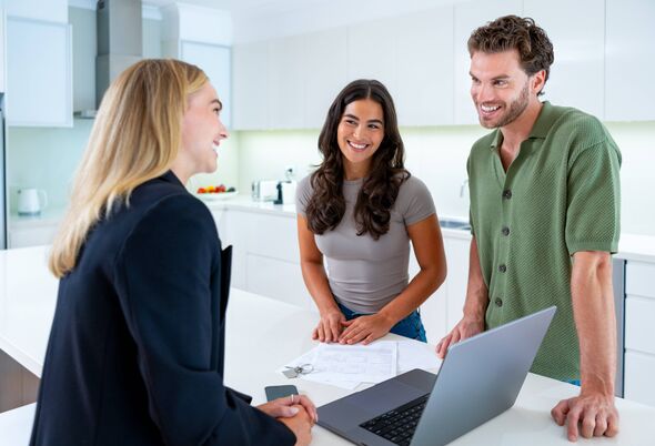 Real estate agent with couple looking at a laptop Real estate agent with couple looking at a laptop