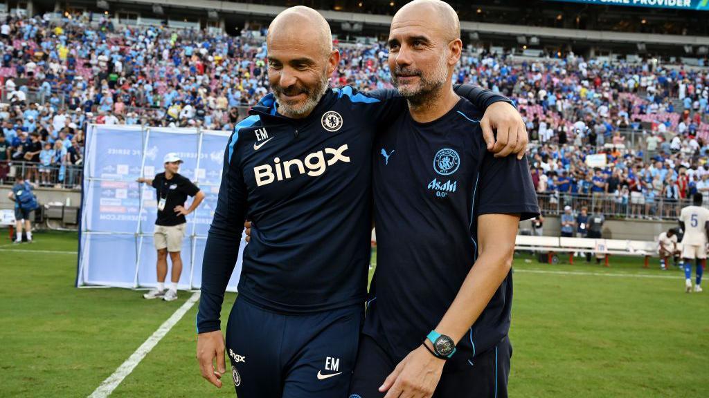 An image of Enzo Maresca, manager of Chelsea, and Pep Guardiola, manager of Man City embracing on the pitch.