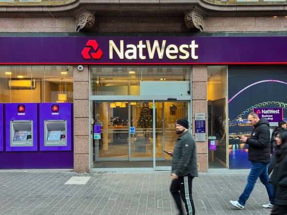 Pedestrians walk past a NatWest bank