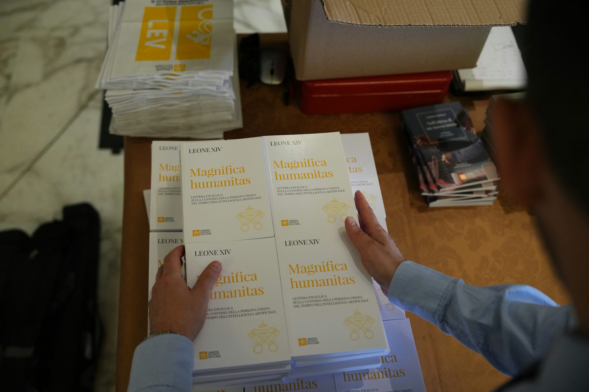 A person holds copies of a document titled Magnifica Humanitas.