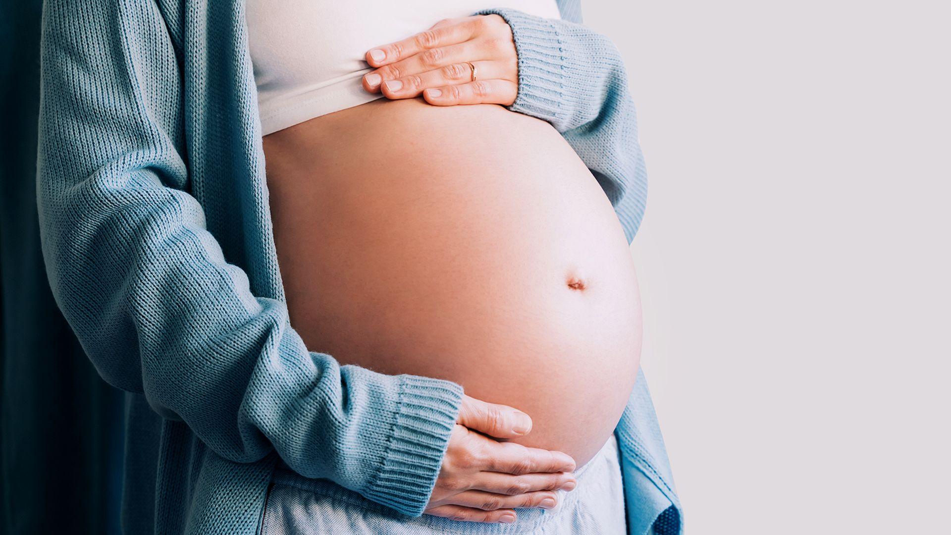 A stock image of an expectant mother touching her baby bump.