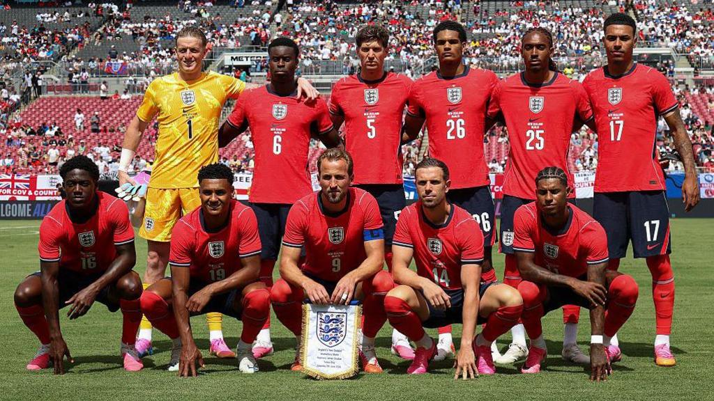 England starting XI pose for a team picture before the friendly match against New Zealand, with captain Harry Kane on the front row holding a pennant. Goalkeeper Jordan Pickford and five outfield players stand behind five crouching players, including Kane, as England wear their red change shirt.