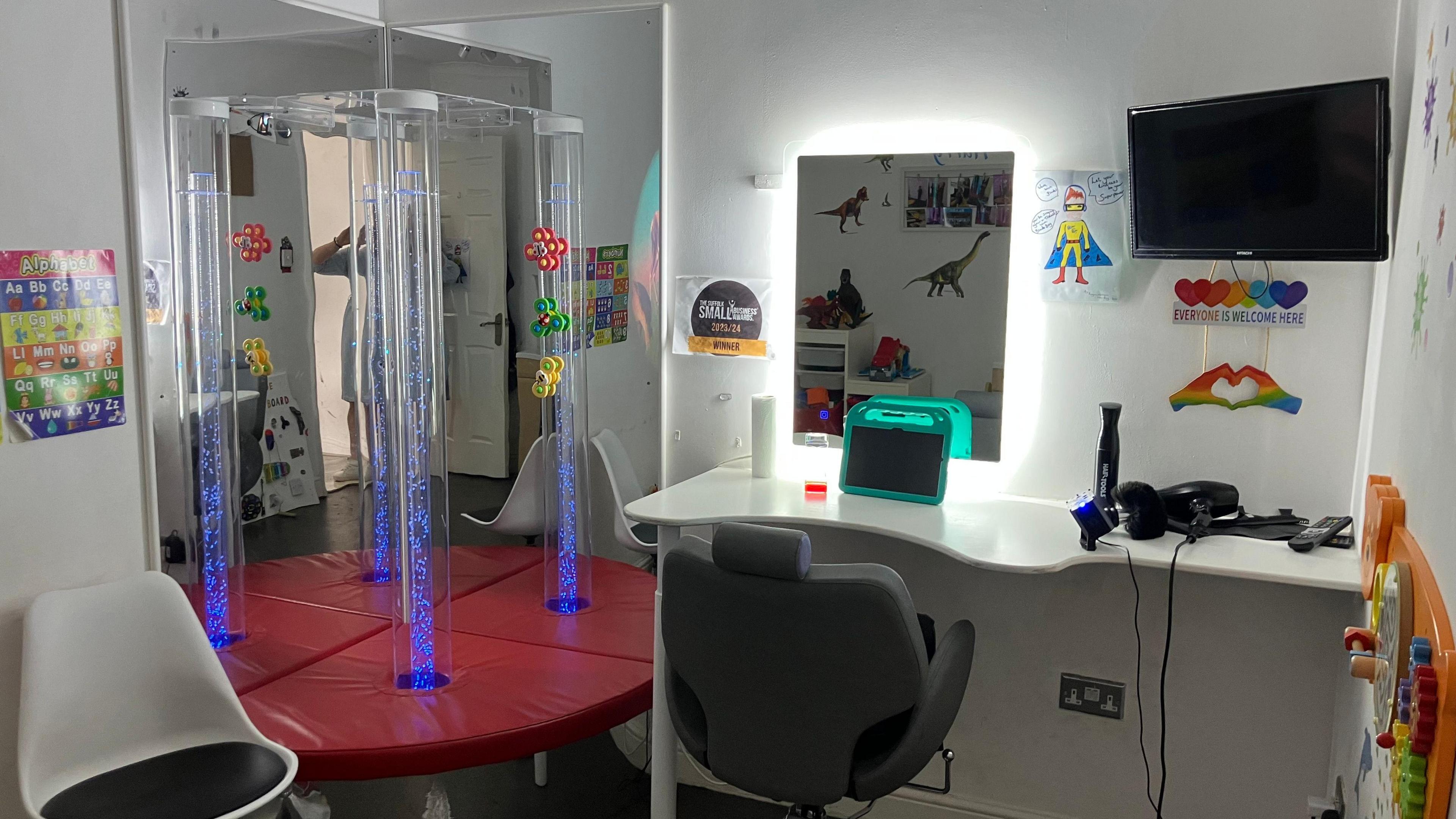 A sensory room featuring chairs, an Ipad, a mirror and toys.