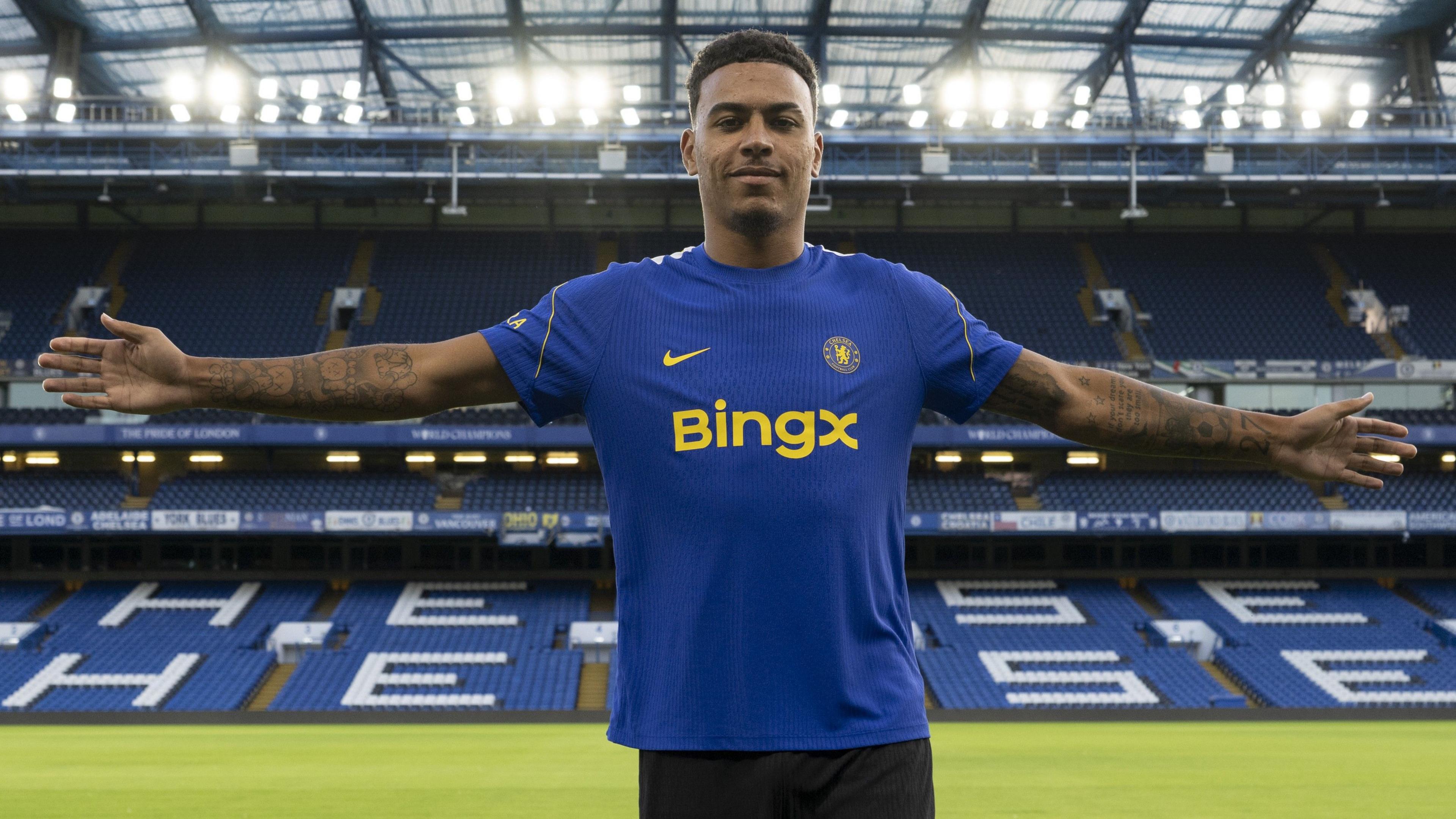 Morgan Rogers stands with his arms outstretched after joining Chelsea
