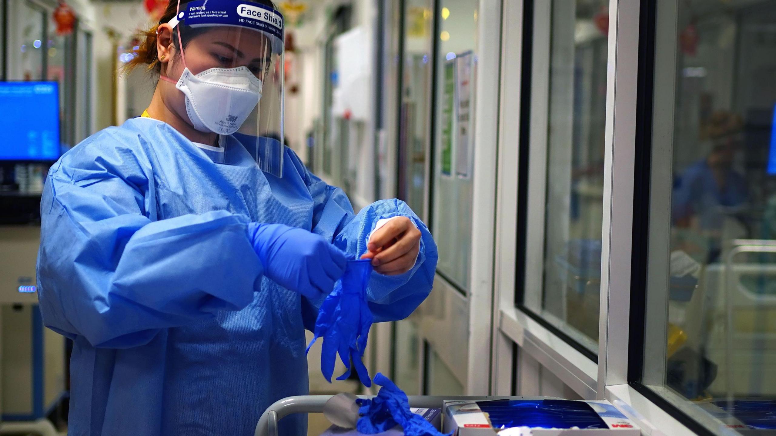 A nurse puts on PPE in a ward for Covid patients