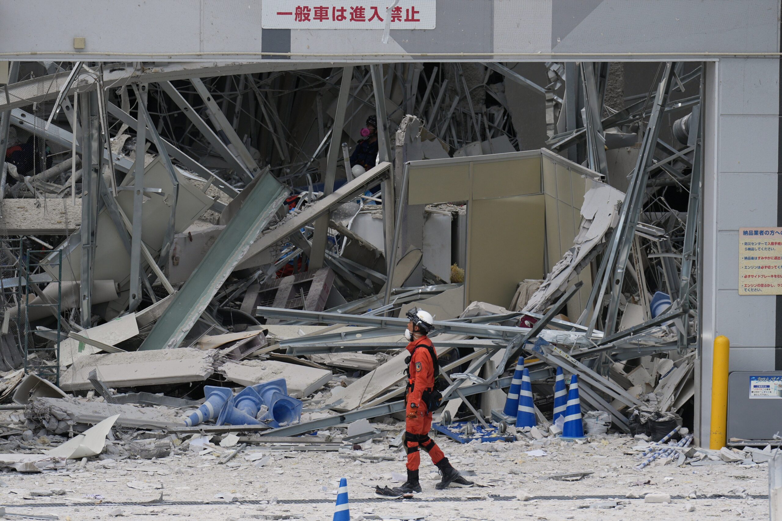 A rescue worker walks in front of AEON Mall, which was damaged by an explosion following an earthquake, is seen in Kashima, Kumamoto Prefecture, southern Japan, on July 29, 2026.