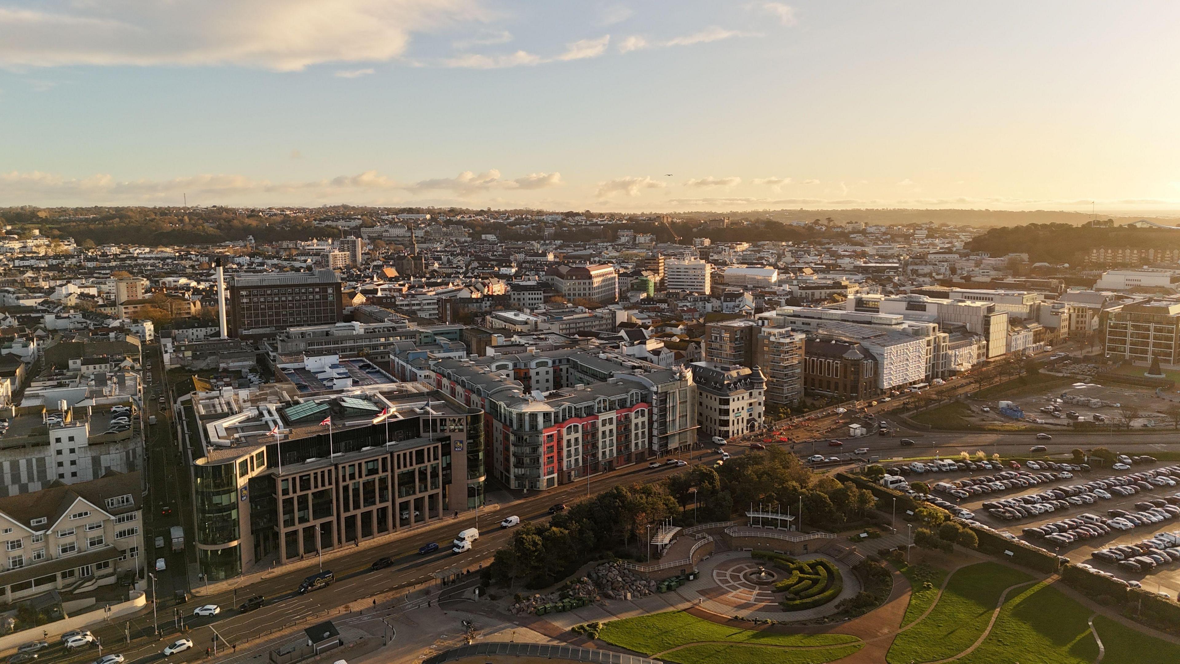Drone shot of St Helier, Jersey. It shows buildings along a road. Behind there are many more buildings stretching off into the distance.