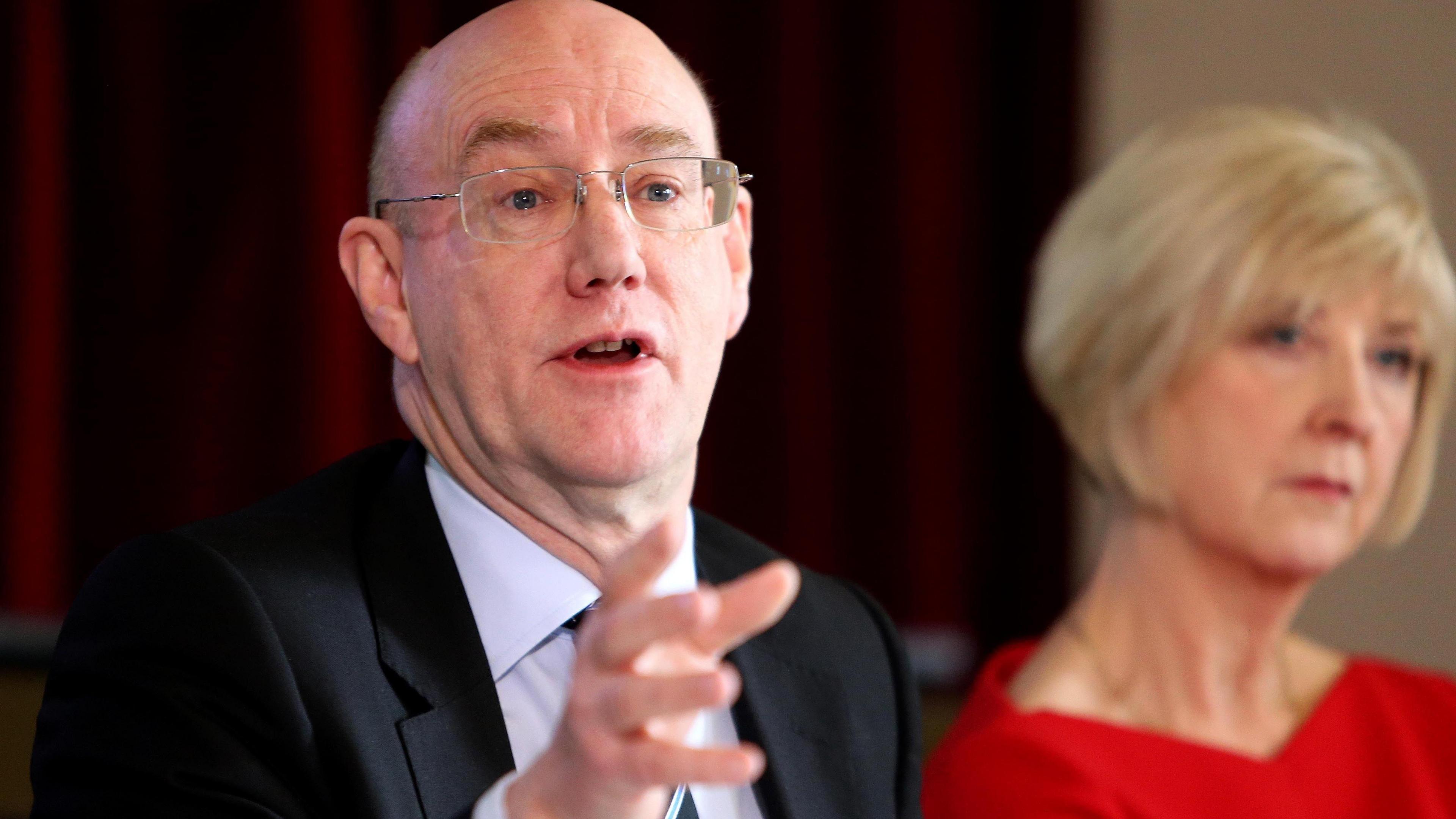 Dr Bill Kirkup answering questions at a press conference in 2015 as he presented the results of the investigation into the Morecambe Bay maternity scandal. He is a man in his 60s with clear glasses wearing a dark suit and white shirt.