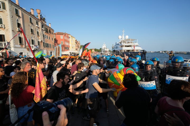 Police officers confront demonstrators gathered to protest against U.S. Ambassador Tilman Fertitta's superyacht, named “Boardwall.”
