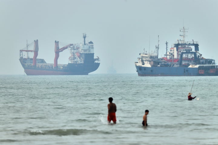 Children wade in the water with cargo ships at anchor in the background and a fisherman nearby, in the Strait of Hormuz off Bandar Abbas, Iran, Tuesday, June 30, 2026. (Amirhosein Khorgooi/ISNA via AP)