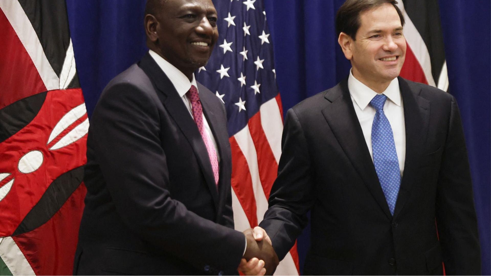 Marco Rubio (R) and Kenya's President William Ruto (L) dressed in dark suits and ties shake hands in New York in September 2025 in front of the Kenyan and US flags.