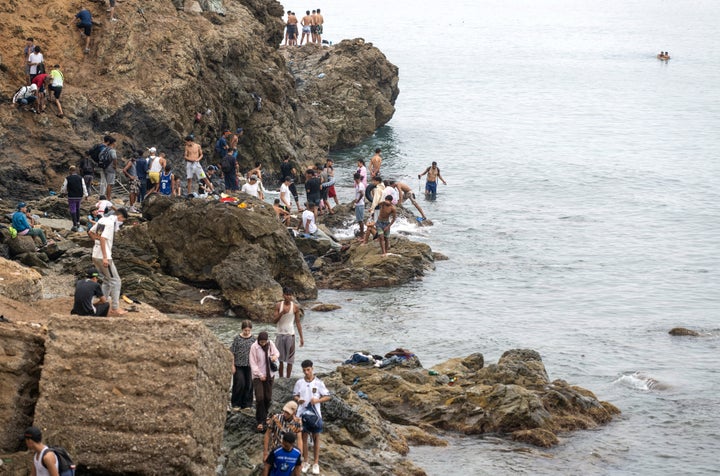 People stand on a shore as they attempt to cross from the Moroccan northern town of Fnideq to the Spanish enclave of Ceuta, Friday, July 31, 2026. (AP Photo)