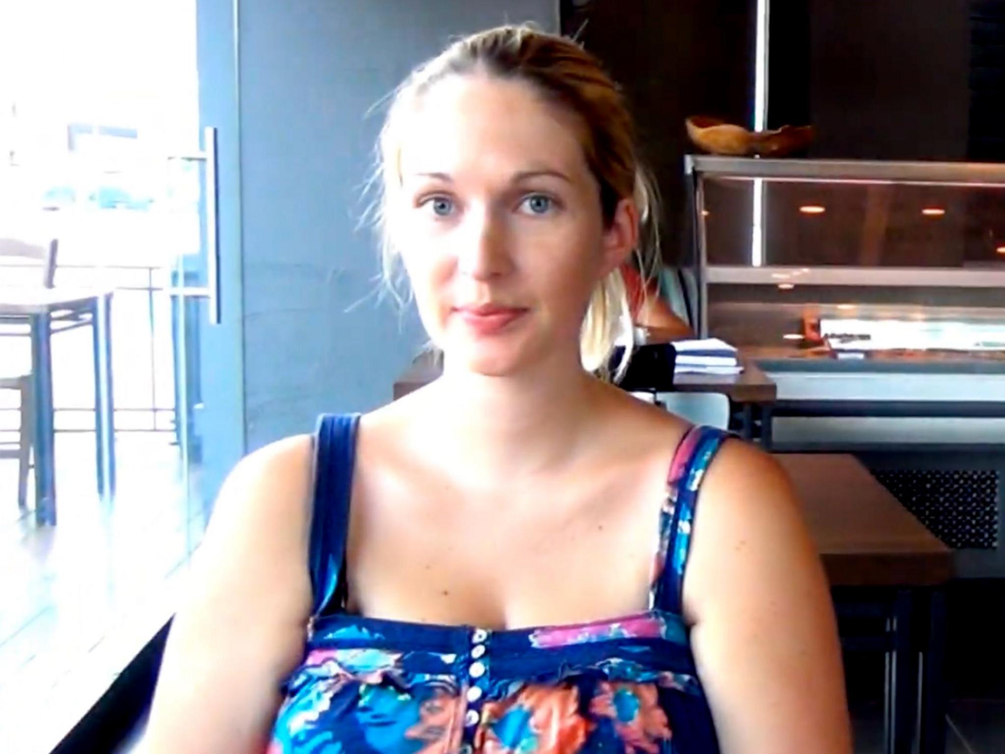 Julie Hodson is sitting in a cafe wearing a colourful dress.