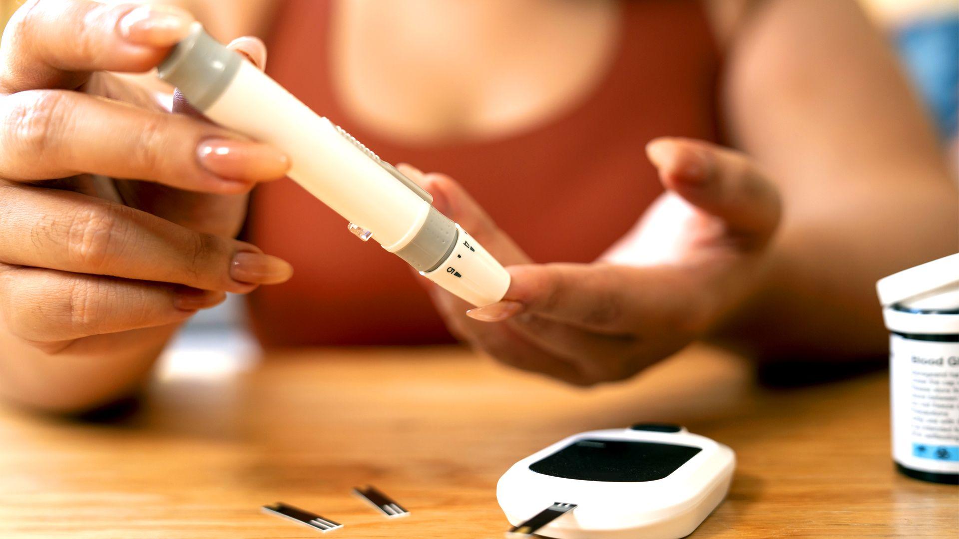 A woman checks her blood glucose reading using a blood test monitor