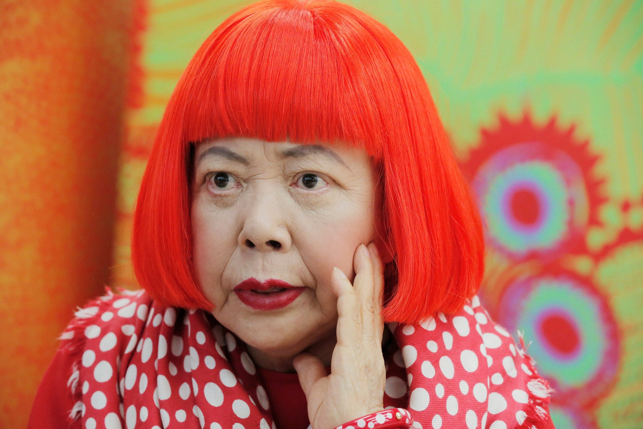 FILE - Japanese avant-garde artist Yayoi Kusama, wearing a bright red wig and a Louis Vuitton polka dot scarf, speaks during an interview at her studio in Tokyo, on Aug. 1, 2012. (AP Photo/Itsuo Inouye, File)