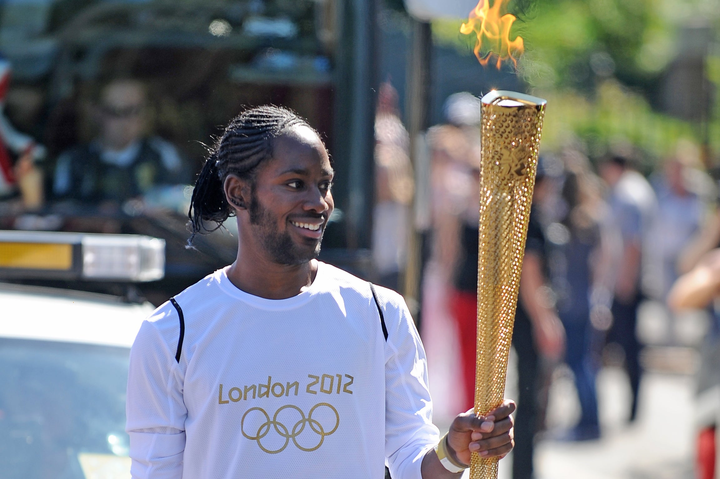 Torchbearer Jason Arday carries the Olympic Flame on the Torch Relay leg between Sutton and Merton, in London, July 23, 2012. (Joe Giddens/LOCOG/PA via AP)