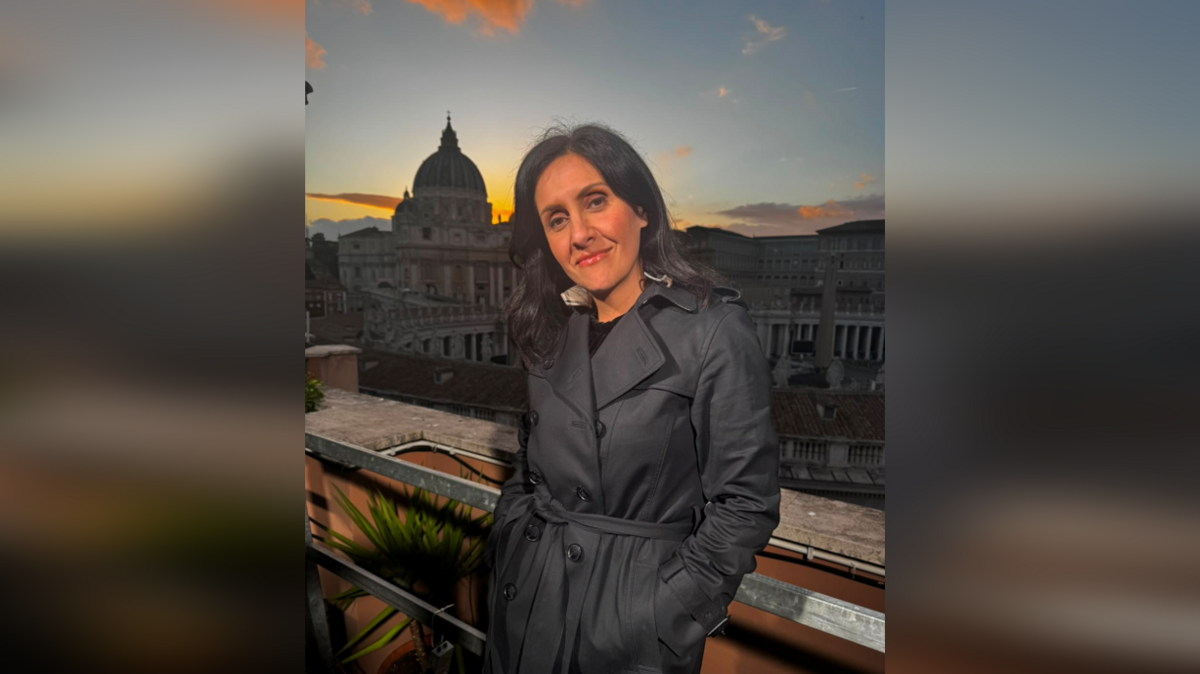  Maryam Moshiri stand in a black coat. The Vatican is in the background