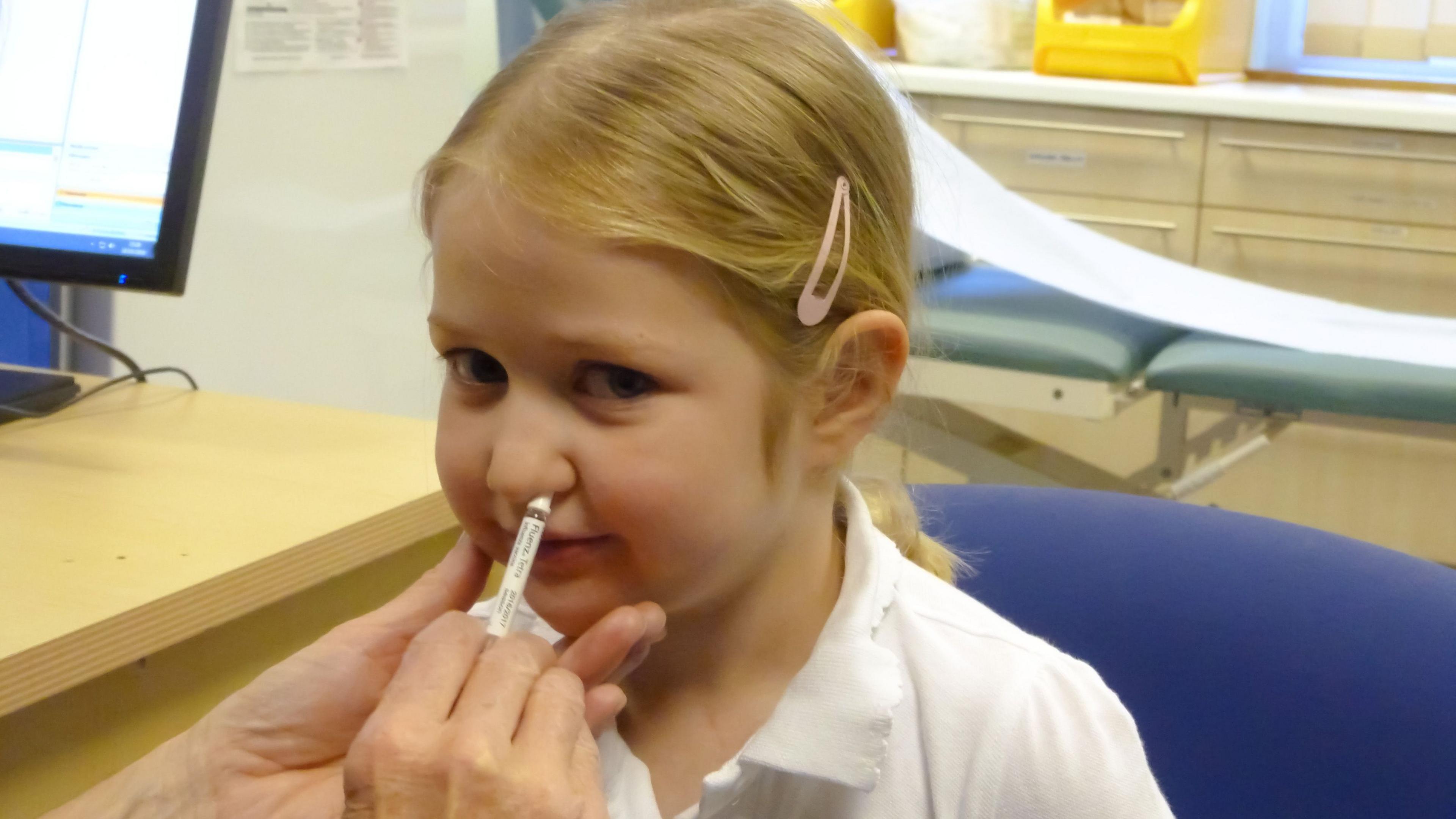 A girl getting her nasal flu vaccine from her GP