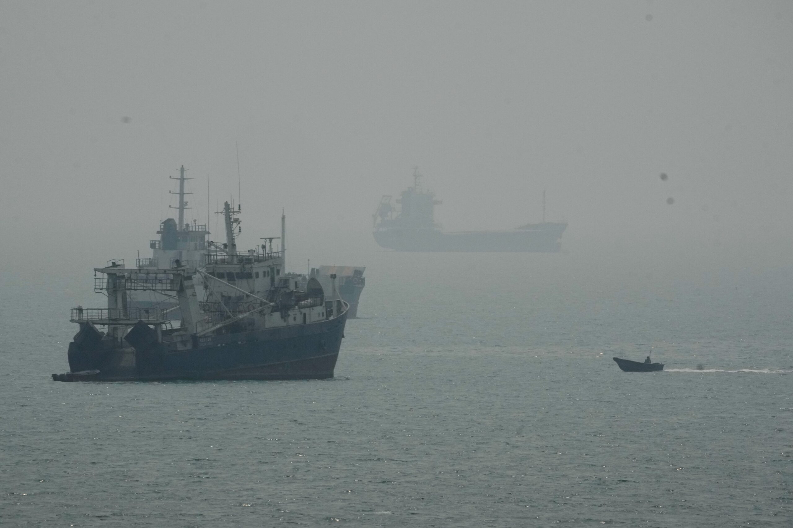 A motorboat travels past commercial vessels anchored amid haze in the Strait of Hormuz off Bandar Abbas, Iran, Monday, Sept. 7, 2026. (AP Photo/Vahid Salemi)